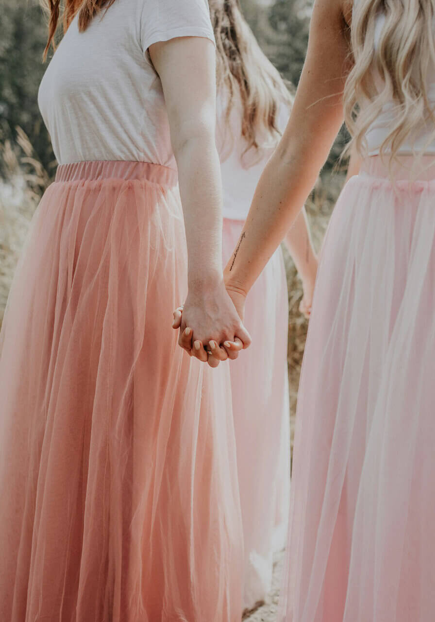 Two people in blush holding hands at a ceremony
